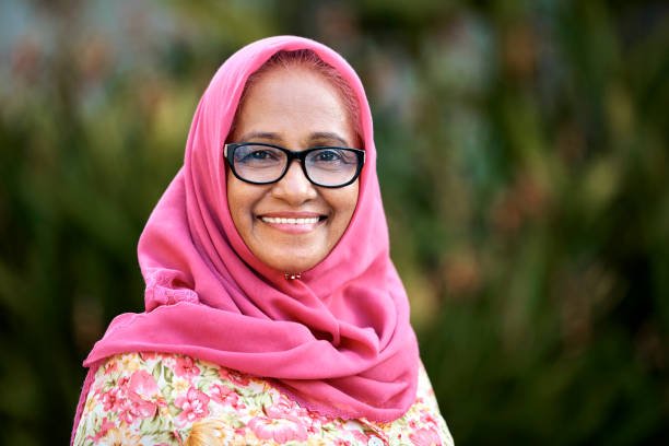 Portrait of confident elderly woman in hijab at yard. Close-up of senior female is wearing eyeglasses. Focus is on her.